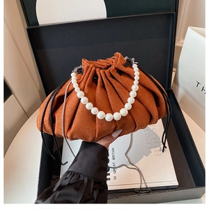 Gros plan du sac seau plissé orange avec poignée en perles et chaîne en métal