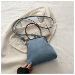 Detail of vintage denim crossbody bag with metal clasp and contrast white stitching