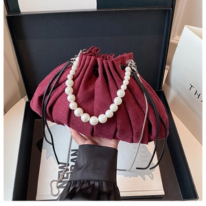 Détail du sac seau bordeaux plissé avec poignée en perles et bandoulière en chaîne