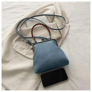 Detail of light blue denim purse with vintage wooden handle and metal kiss-lock closure