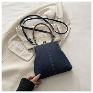 Detailed view of dark blue denim bag with vintage metal clasp and white stitching