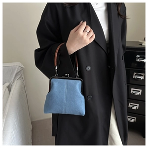 Close-up of denim crossbody bag with vintage metal clasp and brown circular handle