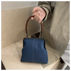 Detail of blue denim doctor bag with dark brown top handle and classic kiss-lock closure