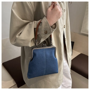 Detail of blue denim purse with vintage silver metal clasp and slim brown leather handle