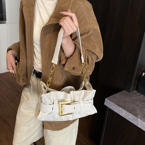 Chic beige pleated cloud bag with gold buckle and chain strap shown on a model