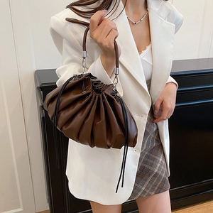 Fashionable dark brown pleated cloud shoulder bag worn by model with white blazer