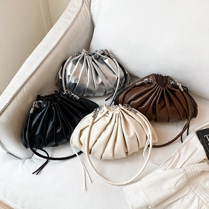 Ruched cloud style bucket bag shown in silver black brown and beige on a sofa