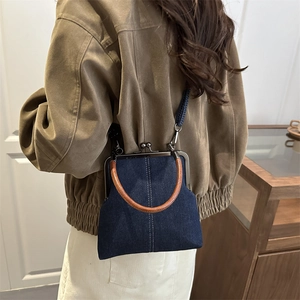 Retro denim crossbody bag with brown leather handles shown on a model's shoulder