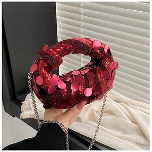 Detailed close-up of red sequin handbag with knot handle and silver chain strap