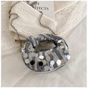 Close-up of silver sequin bag with large metallic discs and fine chain on tweed fabric