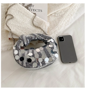 Detailed close-up of a silver sequin crescent evening bag with metallic chain strap
