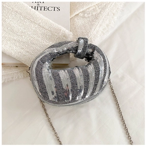 Macro shot of silver sequin handbag texture with metallic chain and knot handle detail