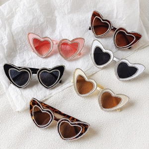 Flat lay of heart-shaped rhinestone sunglasses in pink, black, tortoise, and white colors