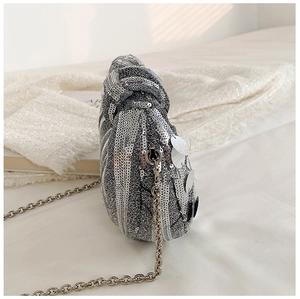 Close-up of silver sequin evening bag featuring twist handle and fine metal chain