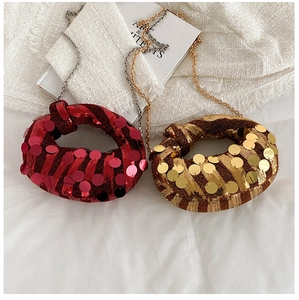 Close-up of red and gold sequined dumpling bags with metal chains on white fabric