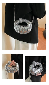 Close-up of silver sequin dumpling bag featuring metal chain and knotted top handle