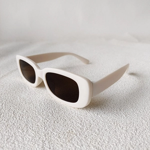 Vue détaillée latérale de lunettes de soleil vintage rectangulaires crème sur tissu