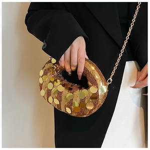 Detail of a gold sequin dumpling bag featuring a delicate metal chain strap on a model