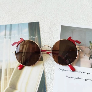 Details einer runden Kinder-Sonnenbrille mit Goldrahmen und rotem Fuchs-Dekor