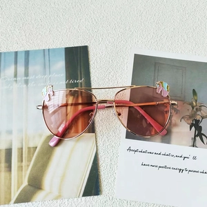 Détail de lunettes aviateur enfant roses, monture or rose et décorations licorne