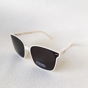 Detail showing white square frame sunglasses with polarized UV400 protective lens stickers