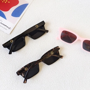 Detail of square sunglasses with gold metal ring accents in black, leopard, and pink