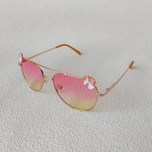 Détail de verres dégradés rose-jaune et montures dorées avec décor de licornes