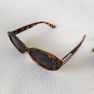 Detail view of tortoiseshell oval sunglasses with UV400 lenses and silver metal accent