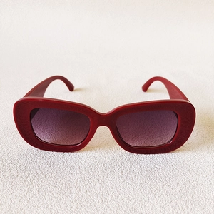 Detailed front view of dark red oval sunglasses with thick frames and gradient purple lenses