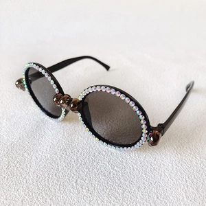 Detail of round sunglasses featuring colorful AB rhinestones and bronze skull metal accents