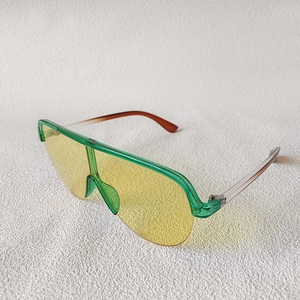 Close-up of oversized semi-rimless sunglasses with green frame and yellow lenses