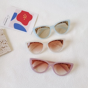 Cat eye sunglasses set in light blue, ivory, and lavender with gold brow detailing