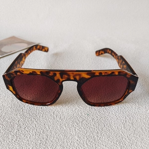 Close-up of retro large square sunglasses featuring a thick tortoiseshell frame and dark lenses