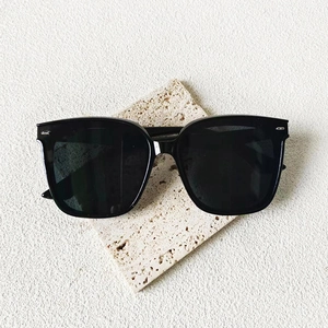 Lunettes de soleil oversize noires classiques avec rivets argentés sur socle en pierre