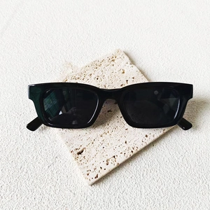 Lunettes de soleil rectangulaires noires modernes avec verres foncés sur support pierre