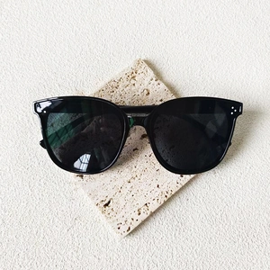 Lunettes de soleil carrées noires avec détails à trois points argentés sur socle