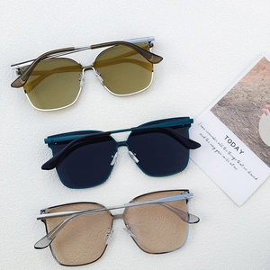 Three pairs of oversized square sunglasses in blue, silver, and gold frames on a white surface