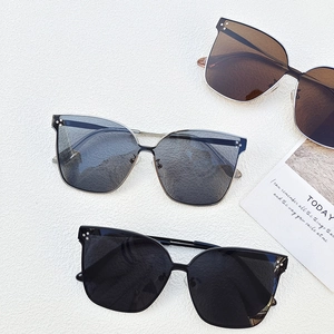 Three oversized cat-eye sunglasses in grey, tea, and black lenses with metal rivets