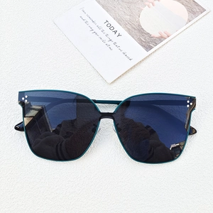 Detailed view of oversized green square sunglasses with three metal rivets and dark lenses