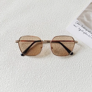 Close-up of retro gold metal kids' sunglasses with amber lenses and black temple tips