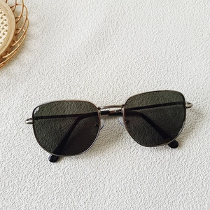 Detalle de gafas de sol retro para niños con montura metálica y lentes oscuras de protección