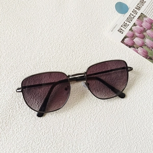 Detalle de gafas de sol de metal con lentes degradadas en violeta sobre superficie texturizada