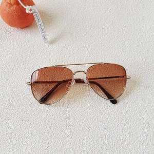 Détail de lunettes aviateur dorées avec verres dégradés marron et finition soignée