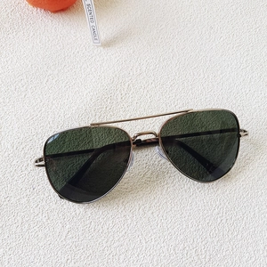 Gros plan de lunettes de soleil aviateur en métal doré avec verres vert foncé