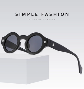 Detail of round black frame glasses with silver square rivets on a white geometric prop