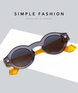 Detail of two-tone sunglasses with dark grey frame, yellow arms, and metal rivets