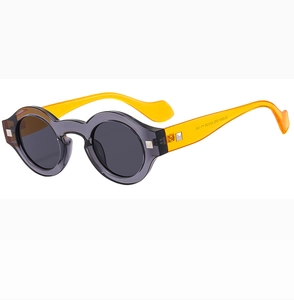Detail view of round retro sunglasses with grey transparent frame and yellow temples