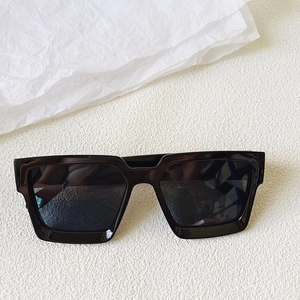 Vue à plat de lunettes de soleil carrées noires oversize sur fond blanc texturé