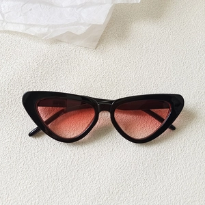 Detail view of vintage cat-eye sunglasses with black frames and gradient red lenses