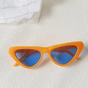 Close-up of retro cat-eye sunglasses with bright orange frame and blue tinted lenses